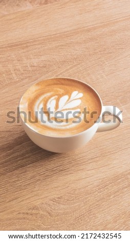Top view of a cup of coffee with latte art tulip on a wooden table background. Home barista and delicious capuccino concept