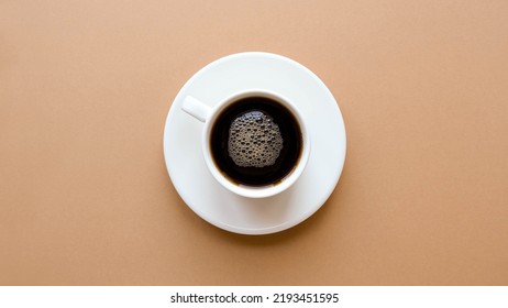 Top View Of A Cup Of Coffee On A Saucer On A Plain Brown Background 