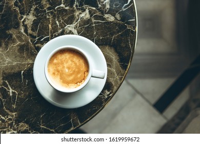 Top view of a cup of fresh aromatic morning coffee on a marble table.