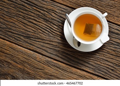 Top view of a cup of tea with tea bag on wooden table