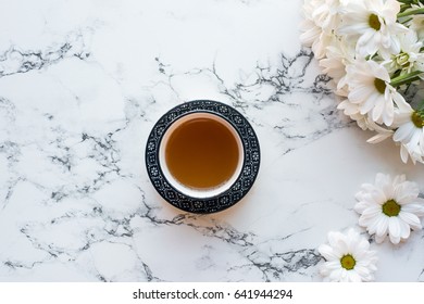 Top View Of Cup Of Tea And Flowers On White Marble Background, Flat Lay