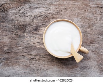 Top View Cup Of Yogurt Or Sour Cream  With Spoon On Old Wooden Background With Copy Space