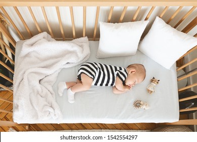 Top view of cute infant baby sleeping on his side in wooden cot
