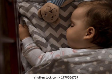 top view Cute little chubby baby girl kid sleeping sweetly in grey crib during lunch rest time in white and pink pajamas with teddy bear at home. Childhood, leisure, comfort, medicine, health concept - Powered by Shutterstock