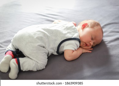 Top View Of Cute Newborn Boy Sleep On His Stomach On Bed Daytime. Mixed Race Asian-German Baby Resting At Home.