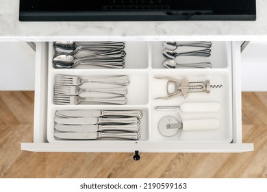 Top View Of Cutlery Box In A Modern Kitchen. Flat Lay Shot Of Open Drawer With Wine Corkscrew, Tablespoons, Teaspoons, Knives And Forks In Open Drawer With Separate Sections