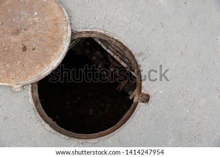 Top view of the dangerous open sewer manhole, a danger to people who walk along the street in the city. The cover lies next to the hatch. Repair of the pipeline under the ground.