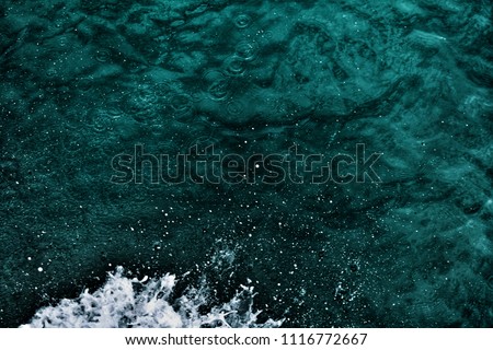 Top view of dark blue ocean water surface background with Splashing wave and white air foam bubble. Rapid sea while sailing boat. This is texture background and free space for designers.