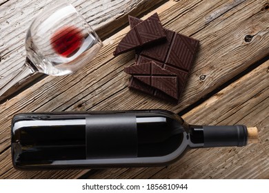 Top view of dark bottle, glass expensive red wine and chocolate on wooden table on white background. Concept of advertising and promotion. Space for text. Flat lay.