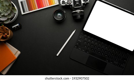 Top view of dark workspace with digital tablet, camera paint tools, stationery and copy space, clipping path - Powered by Shutterstock