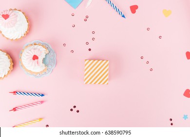 Top view of delicious cupcakes, colorful candles and hearts symbols on pink, birthday party concept