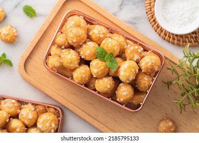 Top view of delicious French Chouquette Choux Pastry dessert Pearl Sugar Puff in a basket on white marble background with a cup of milk tea, afternoon tea concept.