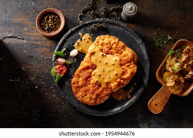 Top view of delicious fried breaded veal escalope with mustard cream sauce served with baked vegetables