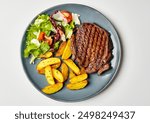 Top view of delicious grilled beef steak and rustic potatoes wedges