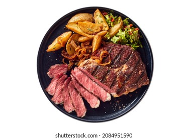 Top view of delicious grilled beef steak and rustic potatoes wedges with vegetable salad served on plate on white background - Shutterstock ID 2084951590