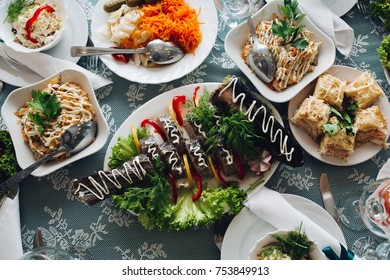 Top View Of Delicious Stuffed Fish With Vegetables And Mayo On Top On Table Surrounded By Different Dishes At Feast.