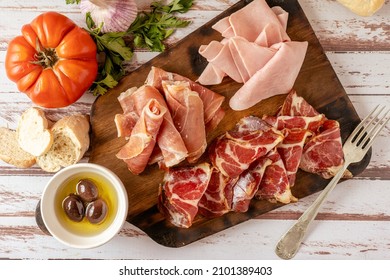 Top View Of A Delicious Table Of Serrano Ham, Cooked Ham And Pickled Pork Butt Accompanied With Black Olives. Appetizer Concept, Animal Protein.