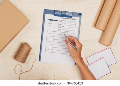 Top view of deliveryman making notes in delivery receipt at table