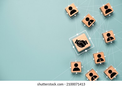 Top view design on blue background of Hand shaking which print screen on wooden cube block which connection with human icon for business deal and agreement concept. - Shutterstock ID 2100071413