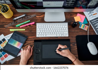 Draufsicht eines Designers, der Grafiktablette verwendet und mit dem Computer arbeitet, während er am Arbeitsplatz im Büro sitzt. Draufsicht auf einen Arbeitsplatz mit Grafiktablett, Tastatur und Computer.