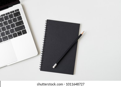 Top View Desk With Laptop Closed Black Cover Notebook And Pencil On White Desk Background