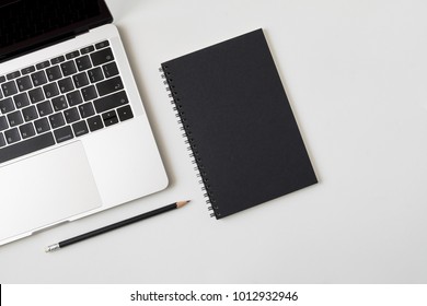 Top View Desk With Laptop Closed Black Cover Notebook And Pencil On White Desk Background