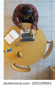 Top view of developer with a laptop, notebook, food and drinks
