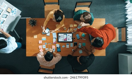 Top view of developer team working together to write idea about Ux Ui design on whiteboard. Smart programmer looking at wireframe prototype at tablet and designing software. Top view. Convocation. - Powered by Shutterstock