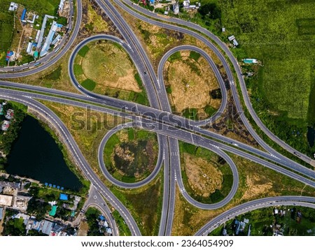 A top view of Dhaka - Bhanga Expressway. beautiful Bangladeshi road.  Aerial top view at highway intersection or road junction with circle movement, cars and trucks traffic.