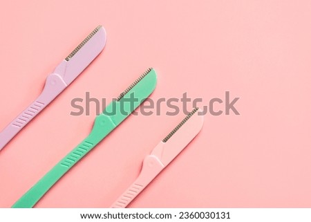 Top view of different dermaplaning tools with space for text over pink background. Skincare products and beauty concept