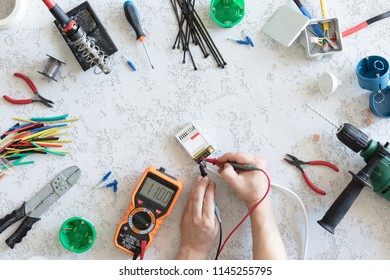 Top view of different electrical tools on white concrete background, flat lay. Tools for an electrician, measurement of voltage 110V and current measurements