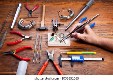 Top view of different goldsmiths tools on the jewelry workplace. Desktop for craft jewelry making with professional tools. Aerial view of tools over rustic wooden background
