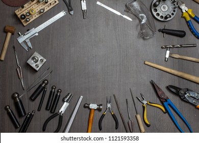 Top view of different goldsmiths tools on the jewelry workplace. Desktop for craft jewelry making with professional tools. Aerial view of tools over rustic wooden background. Poster design. 