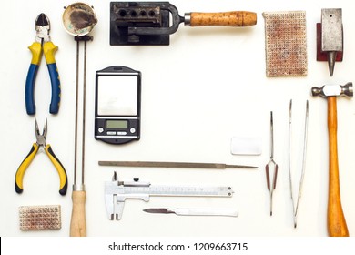 Top View Of Different Goldsmiths Tools On The Jewelry Workplace. Desktop For Craft Jewelry Making With Professional Tools. Aerial View Of Tools Over Isolated White Background. Tabl Repair Goldsmith