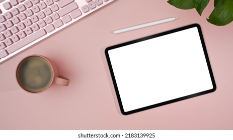 Top view digital tablet with empty display, stylus pen, coffee cup on pink background. Feminine workplace