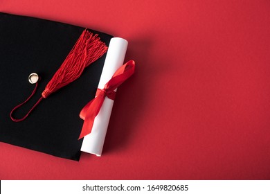 Top View Of Diploma With Beautiful Bow And Graduation Cap With Tassel On Red Background