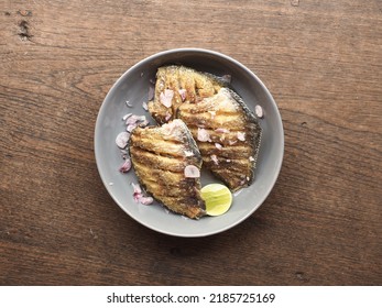 top view dish of deep fried snakeskin gourami fish with shallots and lime on wooden background