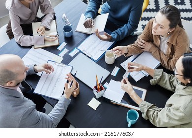 Top View At Diverse Group Of People At Meeting Table In Office Setting Communicating And Gesturing