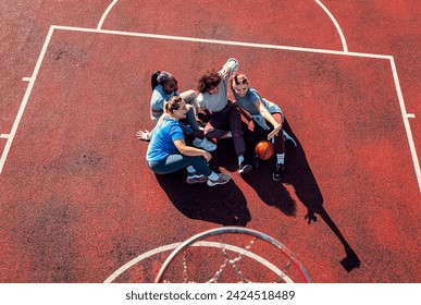 Top view of diverse group of young woman sitting on court resting afrer playing basketball outdoors and making selfie. - Powered by Shutterstock