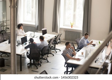 Top view of diverse people working together on computer performing daily routine tasks in coworking space, multiracial millennial men and women busy using devices discussing projects in shared office - Shutterstock ID 1456302323