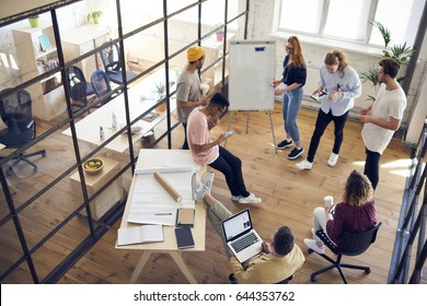 Top view of diversity group working together on architectural project in office interior,young male and female creative graphic designers collaborating during brainstorming using modern technology  - Powered by Shutterstock