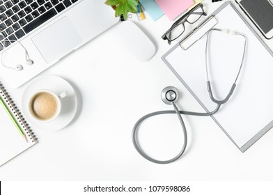 Top View Of Doctor Desk Table With Stethoscope, Coffee  And Blank Paper On Clipboard With Laptop Top View With Copy Space, Flat Lay.