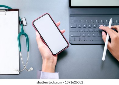 Top View Doctor Hand Holding Smartphone With Blank Screen And Working With Tablet, Black Leather Top Table Background.