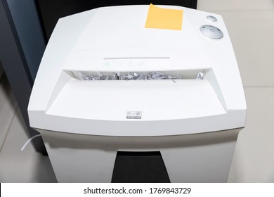 Top view of document shredder with papers overflowed from inside the machine.