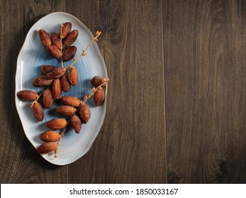 Top View Dried Dates Fruit Ob Oval Plate Above Brown Wooden Table, Copy Space For Text Or Promotional Flyer (Advertising)