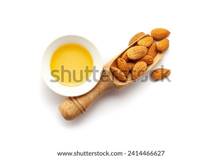 Top view of Dry organic almonds (Prunus dulcis) kernels, in a wooden scoop along with its essential oil.