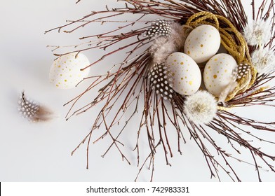 Top view of Easter decorations: eggs with golden spots in a nest of branches, near blow balls and feathers - Powered by Shutterstock