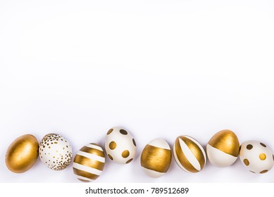 Top view of easter eggs colored with golden paint in differen patterns. Various striped and dotted designs. White background. Copy space.