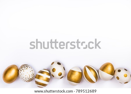 Top view of easter eggs colored with golden paint in differen patterns. Various striped and dotted designs. White background. Copy space.