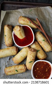 Top View Of Egg Rolls In Sweet And Sour Sauce Over A Dark Rustic Table With Chop Sticks. Garnished With Green Onions. Overhead Table Top View. 